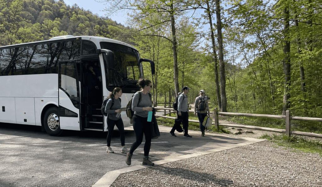 charter bus dropping off a small group near a hocking hills trail area for a columbus day trip